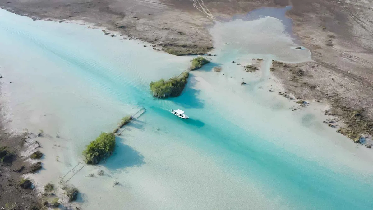 Boat crossing the turquoise bands of the Lagoon of Seven Colours on a Bacalar boat trip, Bacalar Mexico