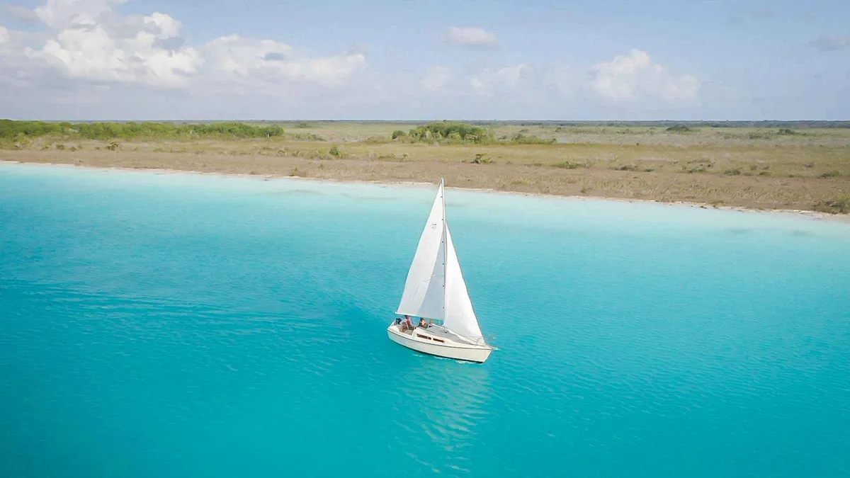 Sailing boat on the still water of Bacalar lagoon at anchor on a group sailing trip, Bacalar Mexico