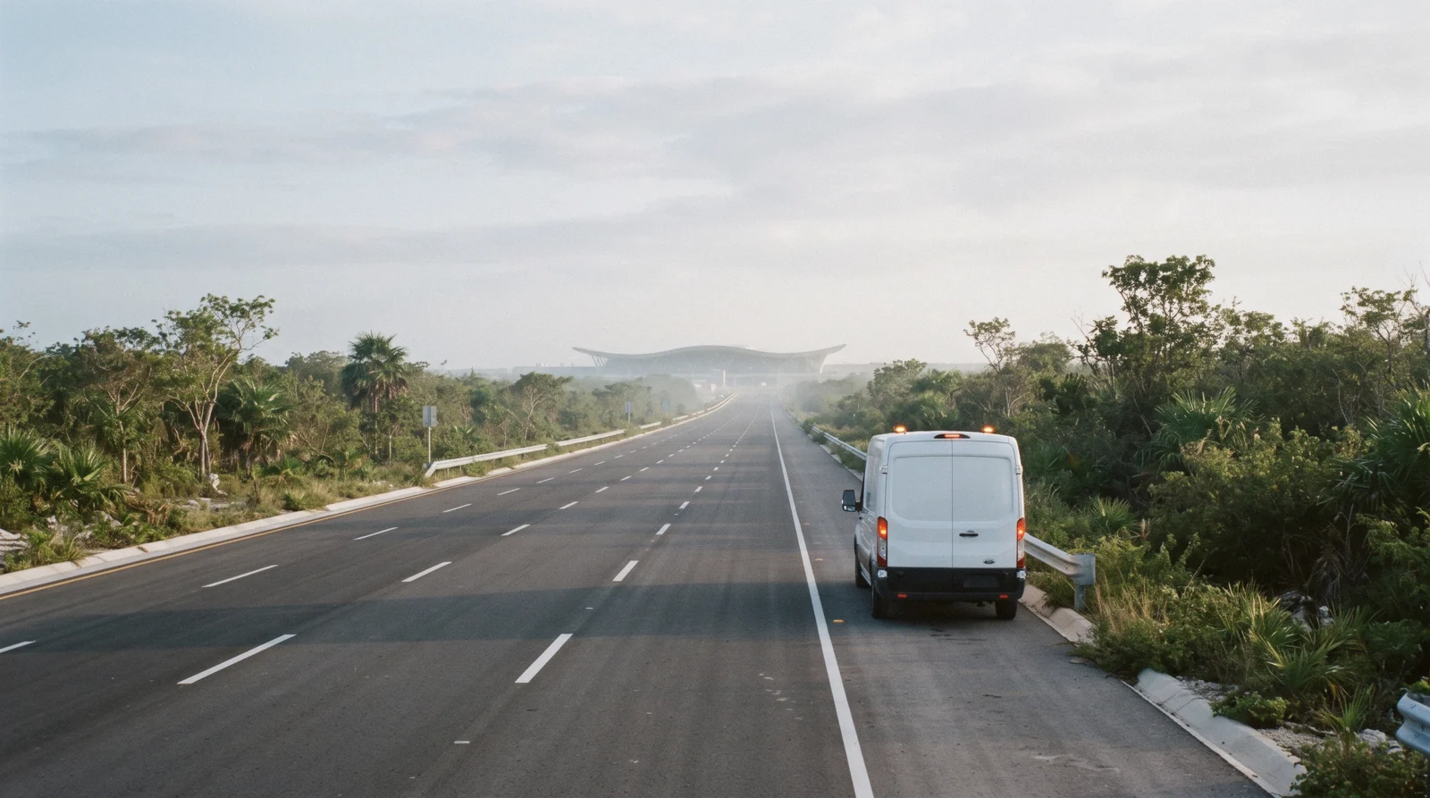 Arrivals road through jungle at Tulum airport with a waiting transfer van, Tulum Mexico